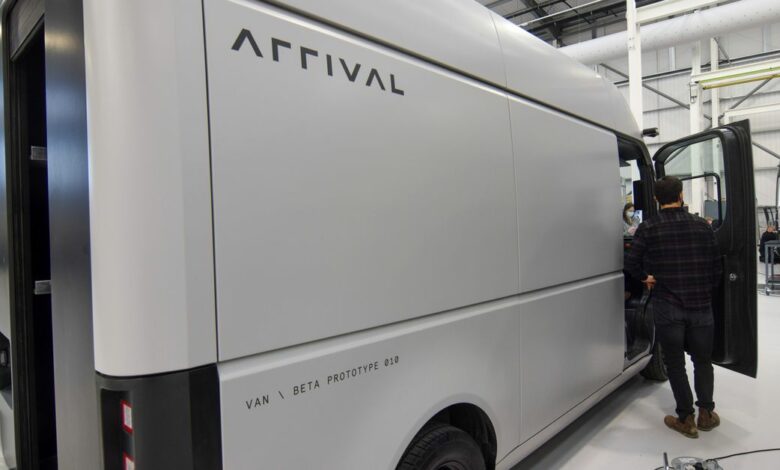 A man stands next to a fully-electric test van built by electric van and bus maker Arrival, in Banbury