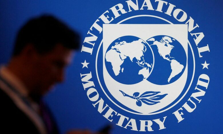 A participant stands near a logo of IMF at the International Monetary Fund - World Bank Annual Meeting 2018 in Nusa Dua