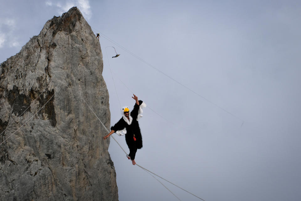 Ein als Adler verkleideter Mann, der am 19. März 2018 in Lescun, Frankreich, auf einem Hochseil in den französischen Pyrenäen läuft, während sein Freund hinter ihm einen Basejump von einer Klippe macht. (Foto von Fred Marie/Art in All of Us/Corbis via Getty Images)