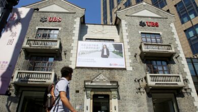 Man walks past a building of Swiss bank UBS in Shanghai