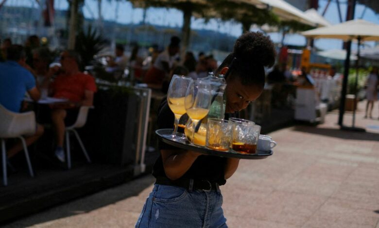A waitress removes drinks from a table in a restaurant in Lisbon
