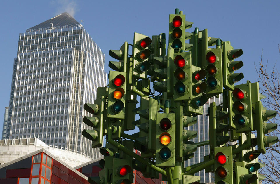 Eine Skulptur, die Dutzende von Ampeln darstellt, blinkt an einem Kreisverkehr in Canary Wharf, dahinter der Canary Wharf Tower, East London, 17. Februar 2003. Montag ist der erste Tag der Staugebühr - eine feste Gebühr für die meisten Autofahrer, die ins Zentrum von London einfahren. TPORT REUTERS/Toby Melville TM