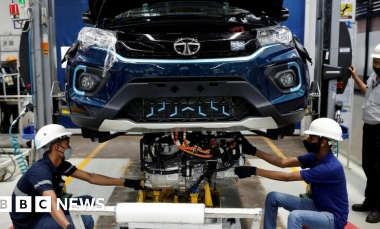 Workers install the electric motor inside a Tata Nexon electric sport utility vehicle (SUV) at the Tata Motors plant in Pune, India.