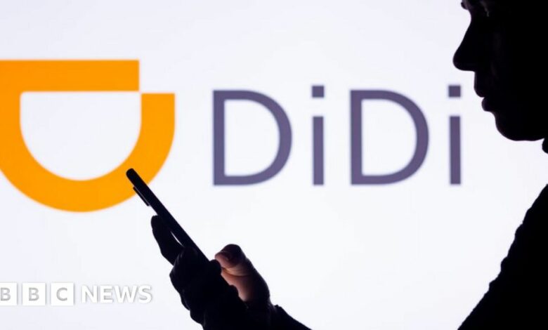 Silhouette of woman holding a smartphone with the Didi Chuxing logo in the background.