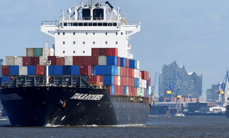 A container ship leaves the port in front of famous landmark Philharmonic Hall in Hamburg