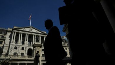 Workers are silhouetted as they walk past the Bank of England, in London