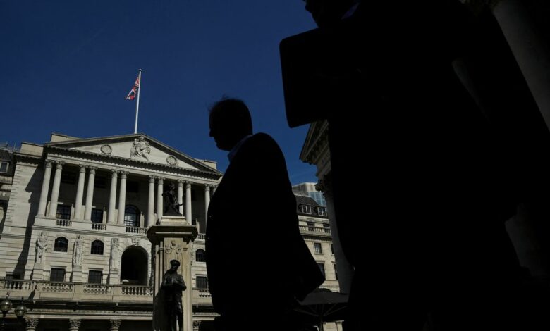 Workers are silhouetted as they walk past the Bank of England, in London