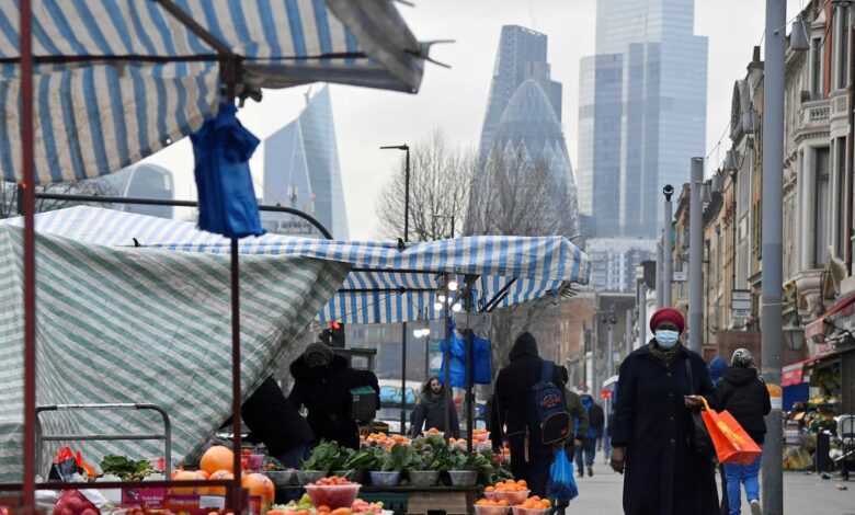 People shop at market stalls, with skyscrapers of the CIty of London, Britain financial district seen behind, in London