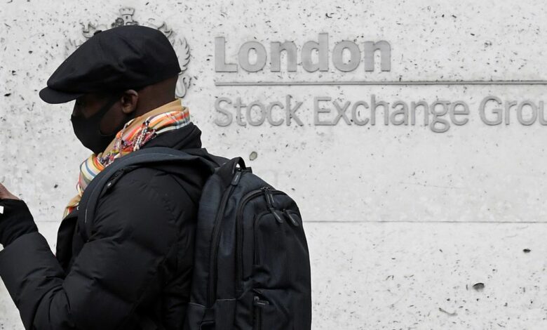 A man wearing a protective face mask walks past the London Stock Exchange Group building in the City of London financial district, whilst British stocks tumble as investors fear that the coronavirus outbreak could stall the global economy, in London