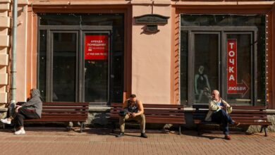 People rest on benches near a window of business premises put out for rent in Moscow