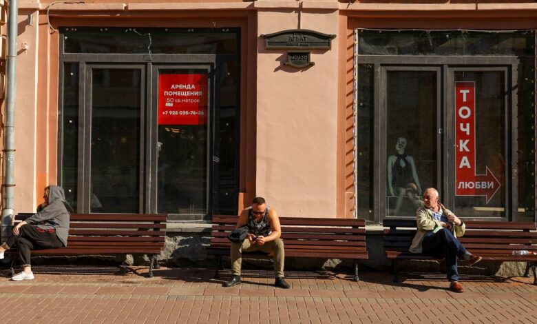 People rest on benches near a window of business premises put out for rent in Moscow