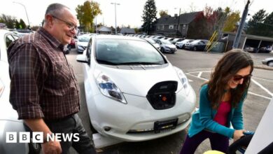 Man and woman learning how to charge second hand electric car