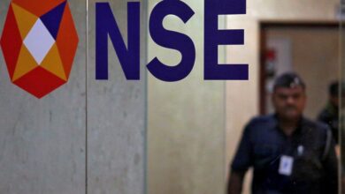 A security guard walks past the logo of the National Stock Exchange inside its building in Mumbai