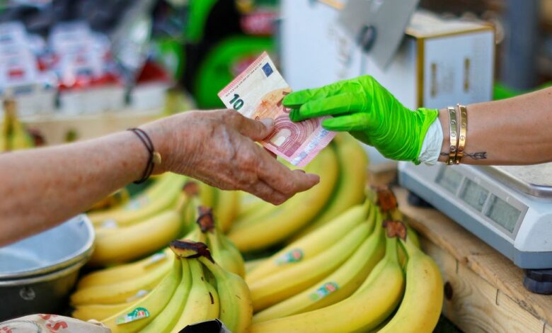 A shopper pays with a ten Euro bank note at a local market in Nice