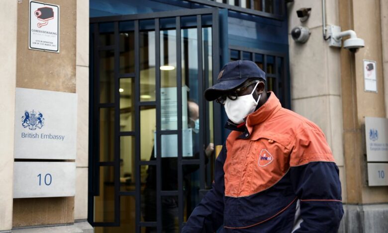 A PostNL employee is seen at the entrance of the UK Mission to the EU