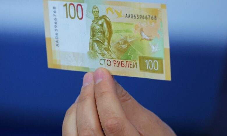 Deputy Governor of the Bank of Russia Sergey Belov holds the newly designed Russian 100-rouble banknote during a presentation in Moscow
