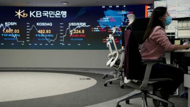 A currency dealer works in front of an electronic board showing the Korea Composite Stock Price Index (KOSPI) at a dealing room of a bank in Seoul