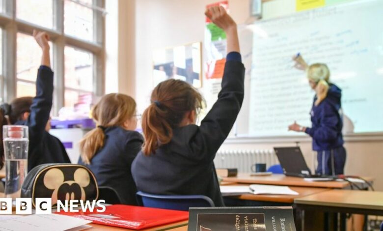 Pupils raise their hands in a classroom
