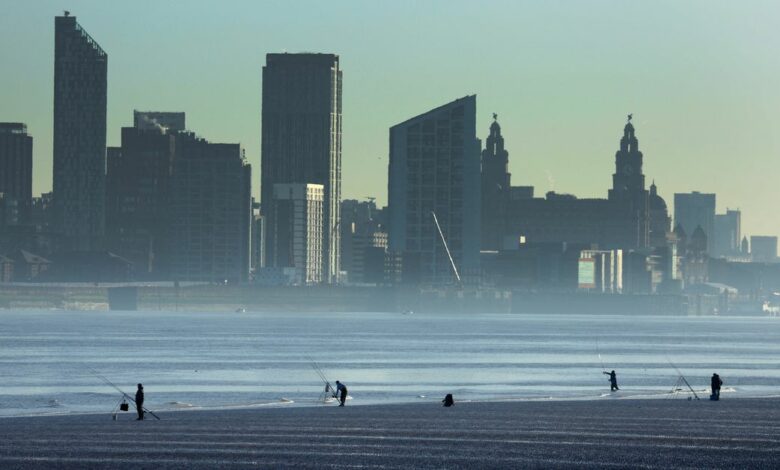 People fish in front of the skyline of Liverpool on the banks of the River Mersey in Wallasey