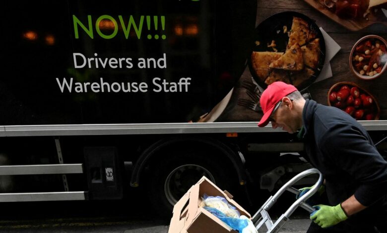 Lorry driver passes a sign on the side of his vehicle advertising for jobs as he makes a delivery, in London