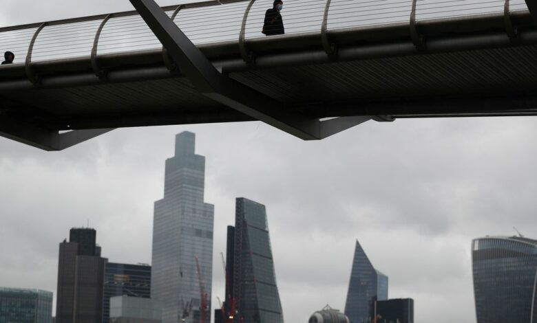 People walk across Millennium Bridge with the City of London financial district seen behind, amid the coronavirus disease (COVID-19) pandemic, in London