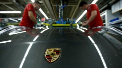 Employees of German car manufacturer Porsche install the windshield of a Porsche 911 at the Porsche factory in Stuttgart-Zuffenhausen
