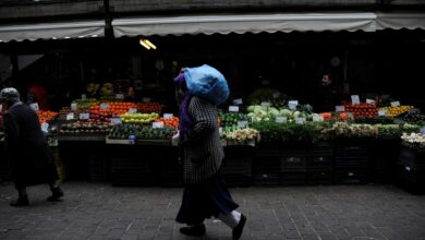 A woman walks past a vegetable market in central Athens
