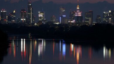 A skyline of skyscrapers is reflected in the Vistula river in the evening in Warsaw