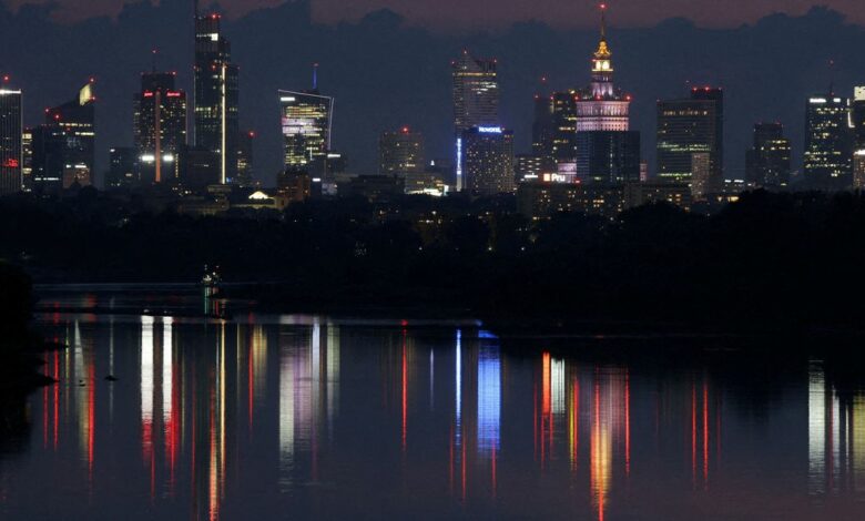 A skyline of skyscrapers is reflected in the Vistula river in the evening in Warsaw