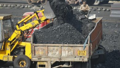 A worker sits on a truck being loaded with coal at a railway coal yard on the outskirts of Ahmedabad