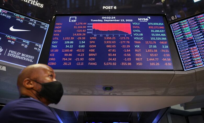 A trader stands beneath a screen on the trading floor displaying the Dow Jones Industrial Average at the New York Stock Exchange (NYSE) in Manhattan, New York City