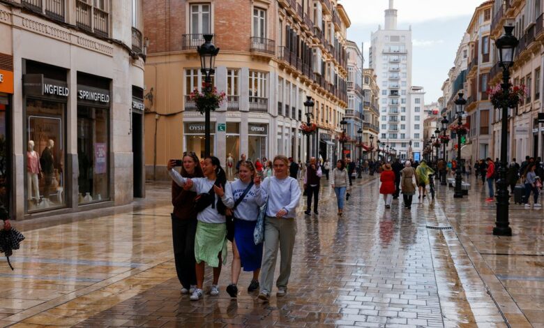Tourists walk along a shopping street in central Malaga