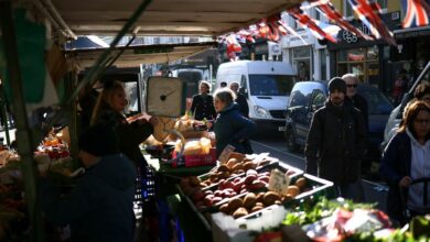 People browse food items on display at a fruit and vegetable stall at Portobello Road Market in London