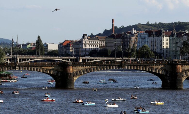 People ride pedal boats on the Vltava river in Prague