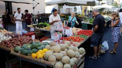 People buy fruit and vegetables in a street market in Rome